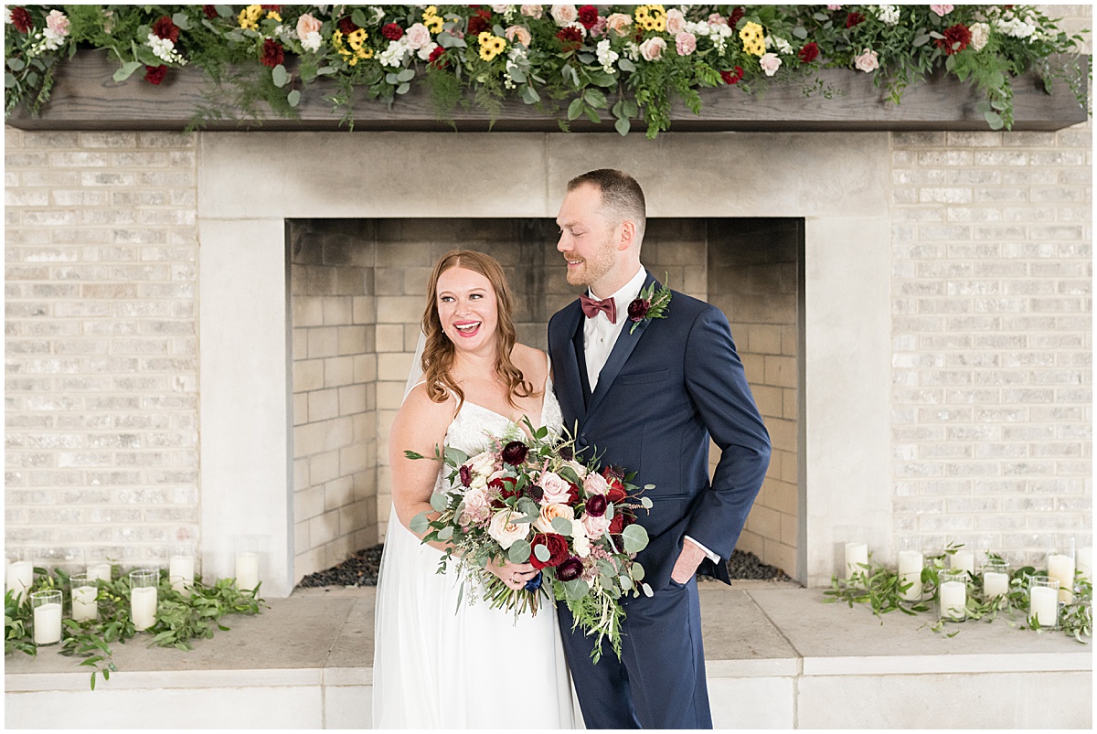 Bride and groom in front of floral filled fireplace at Iron & Ember events wedding in Carmel, Indiana
