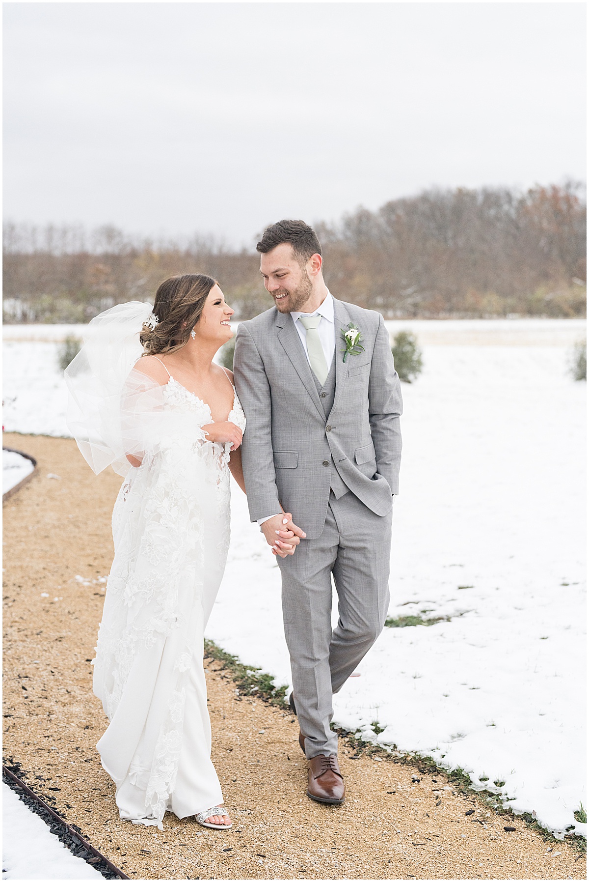 Bride and groom walk on snowy trail after wedding at New Journey Farms