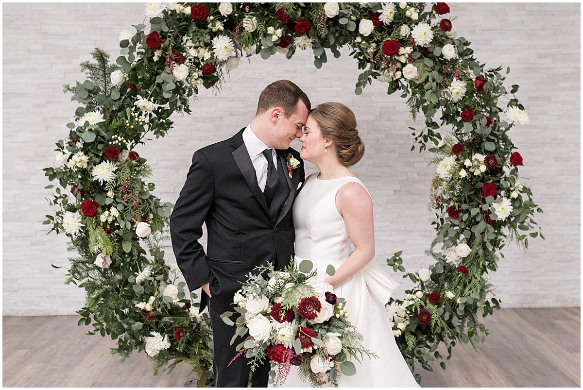 Bride and groom get close under flower archway at Allure on the Lake wedding in Chesterton, Indiana