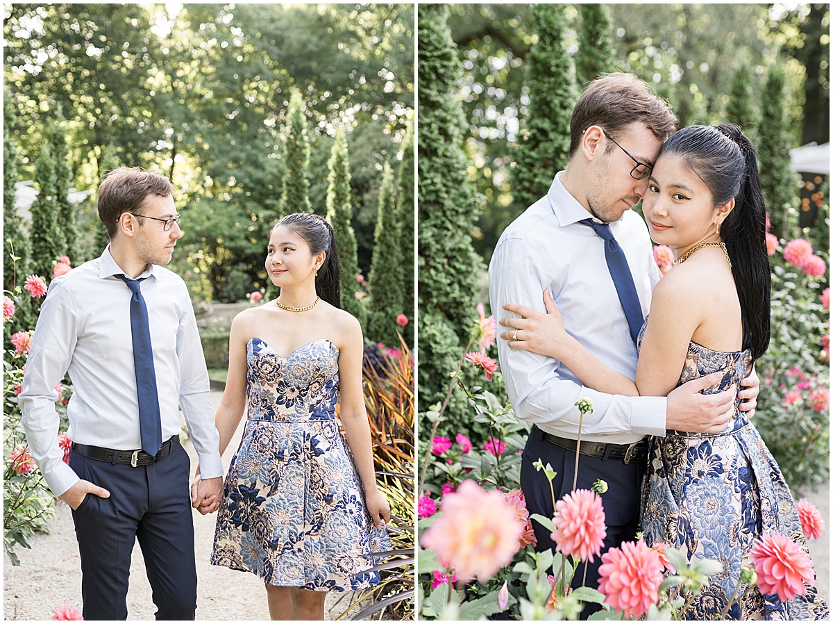 Couple hold hands in garden of pink flowers during garden engagement photos at Newfields in Indianapolis