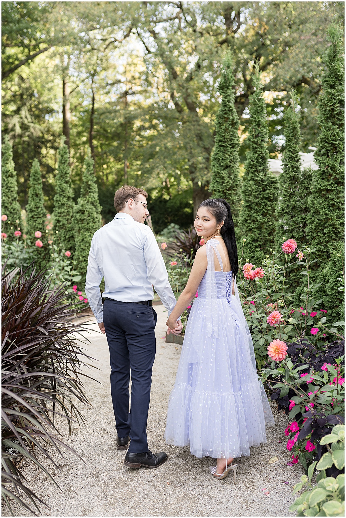 Couple hold hands on path during garden engagement photos at Newfields in Indianapolis