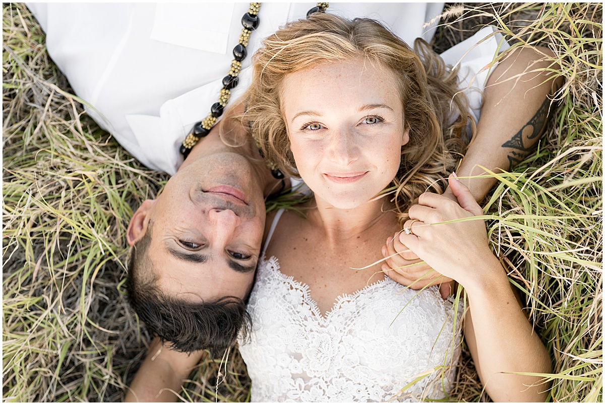 Couple laying in grass at South Point Hawaii elopement photographed by Victoria Rayburn Photography