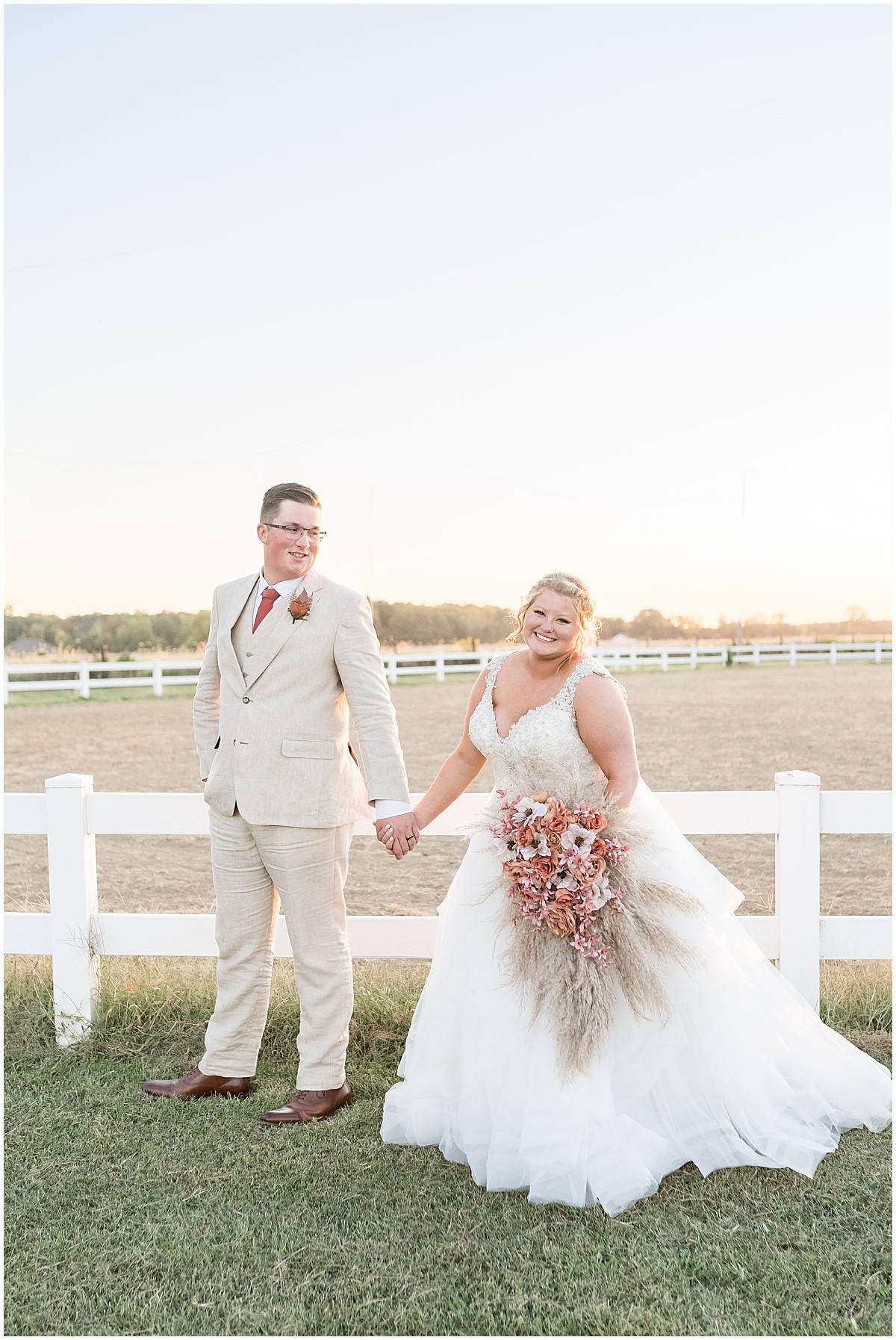 Bride and groom hold hands during sunset photos after boho-inspired Miami County Fairgrounds wedding in Peru, Indiana photographed by Victoria Rayburn Photography