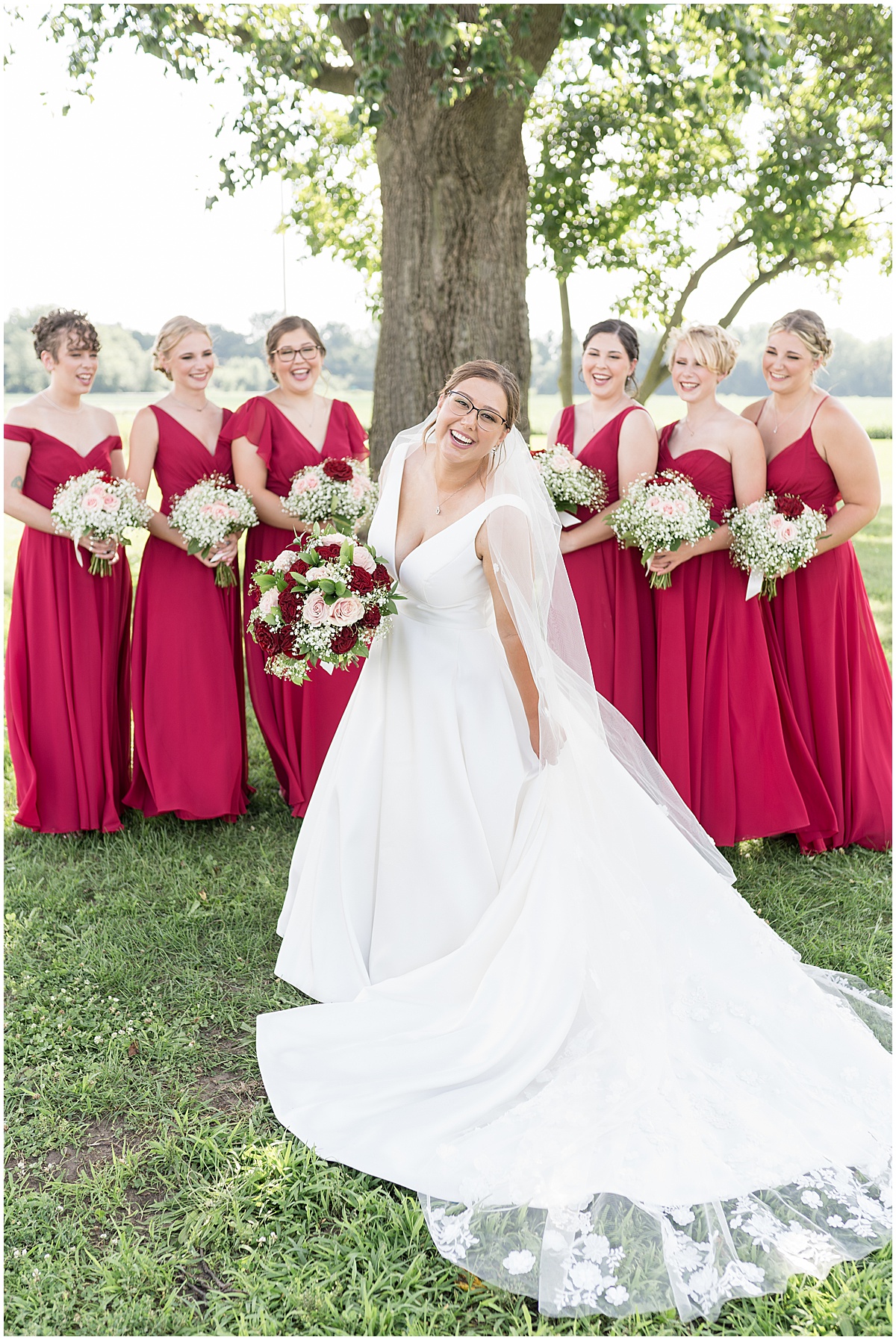 Bride shows off dress in front of bridesmaids at Churchill Farms wedding in Lake Village, Indiana photographed by Victoria Rayburn Photography