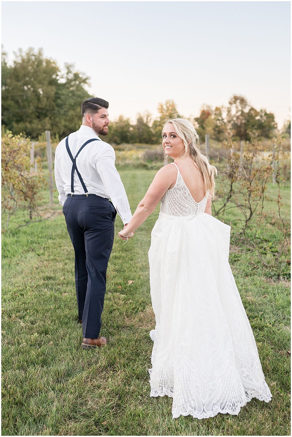 Newlyweds walking through vineyard at wedding at Finley Creek Vineyards in Zionsville, Indiana photographed by Victoria Rayburn Photography