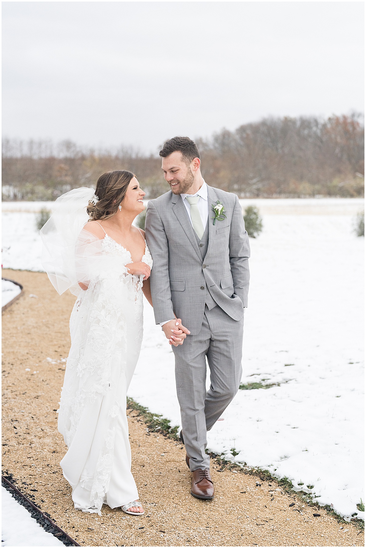 Bride and groom walk on path in snow after wedding at New Journey Farms in Lafayette, Indiana photographed by Victoria Rayburn Photography