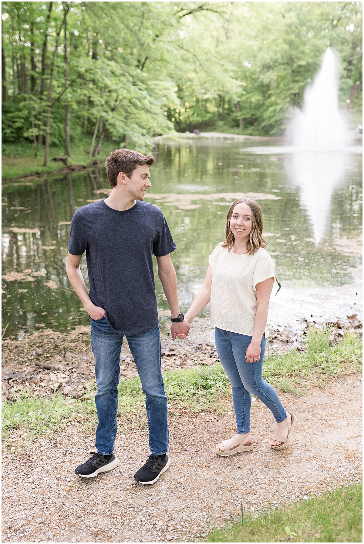 Couple walk by water during engagement photos at Holcomb Gardens in Indianapolis.