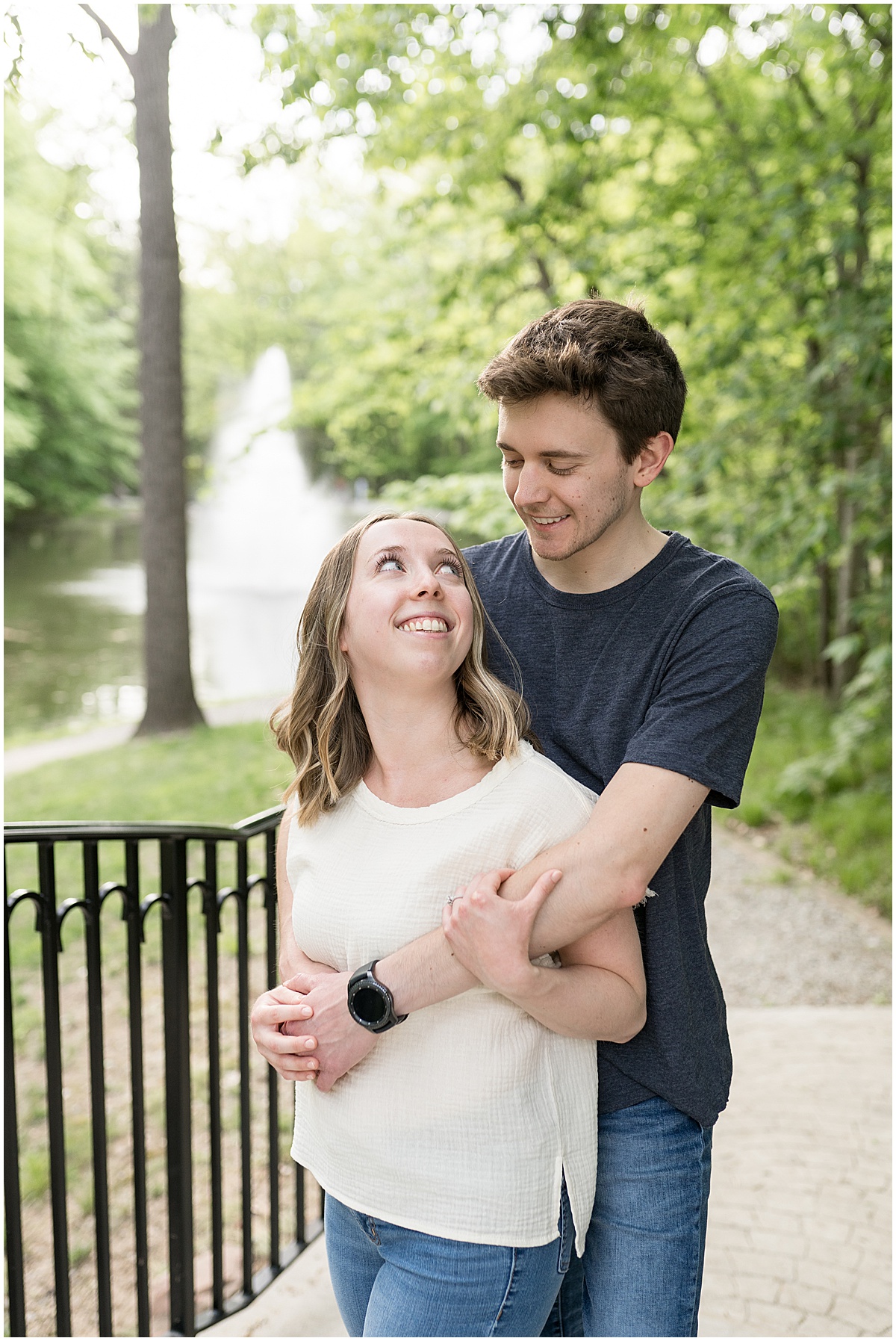 Couple hug in front of fountain at engagement photos at Holcomb Gardens in Indianapolis.