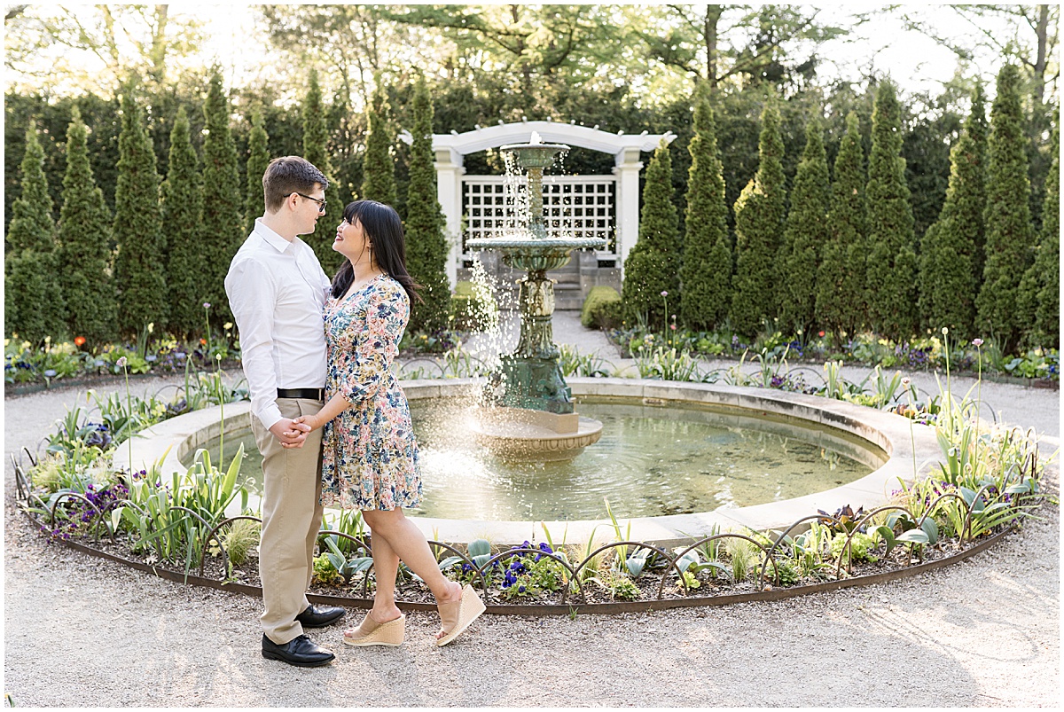 Couple in garden by fountain during engagement photos at Newfields in Indianapolis.