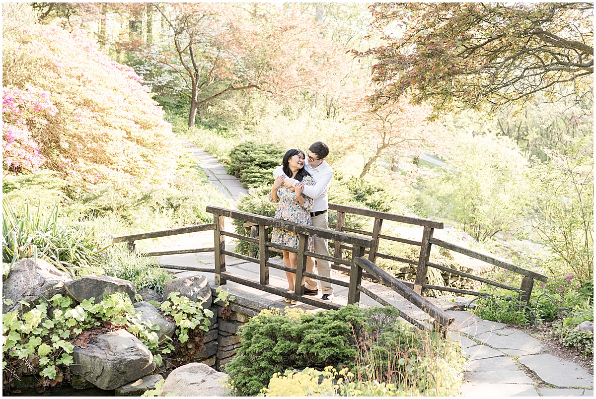 Couple walk on garden bridge at engagement photos at Newfields in Indianapolis.