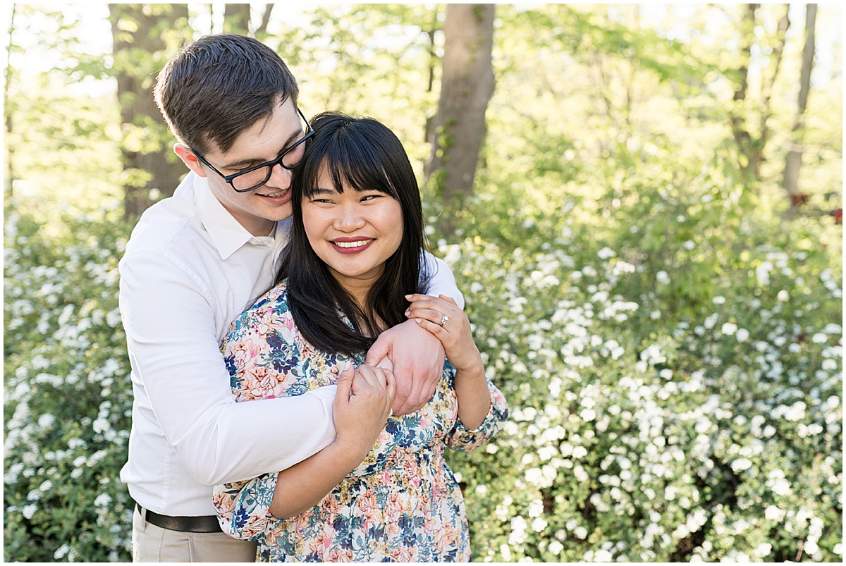 Couple hug in flower field at engagement photos at Newfields in Indianapolis.