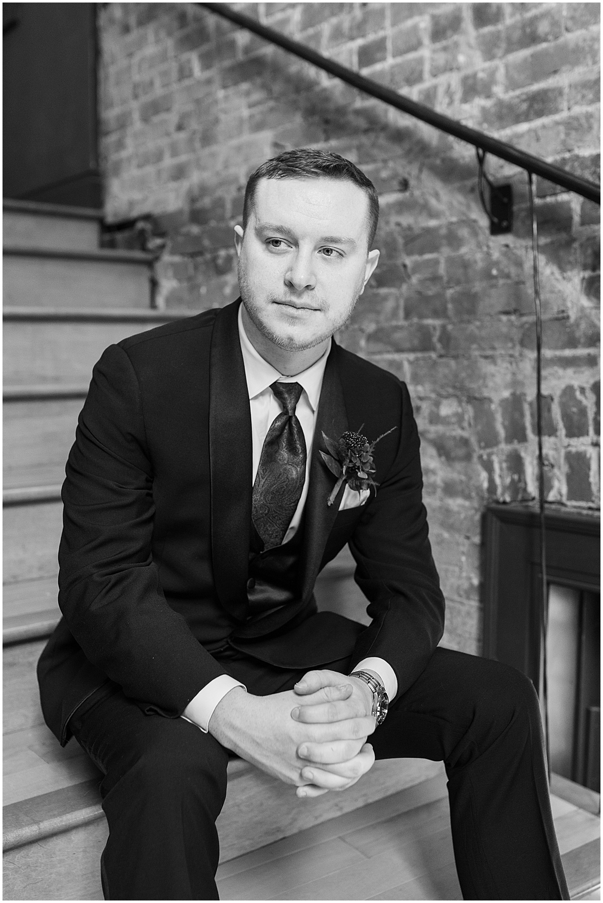 Groom sitting on stairs and looking over shoulder before Historic Saint Joseph Hall wedding in Indianapolis