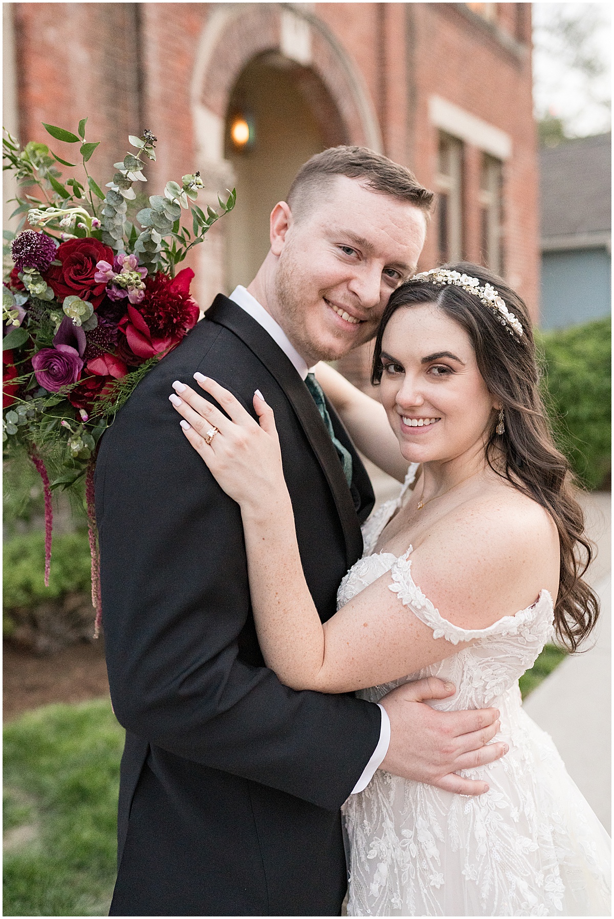 Bride and groom smiling at camera with bouquet in front of venue Historic Saint Joseph Hall wedding in Indianapolis