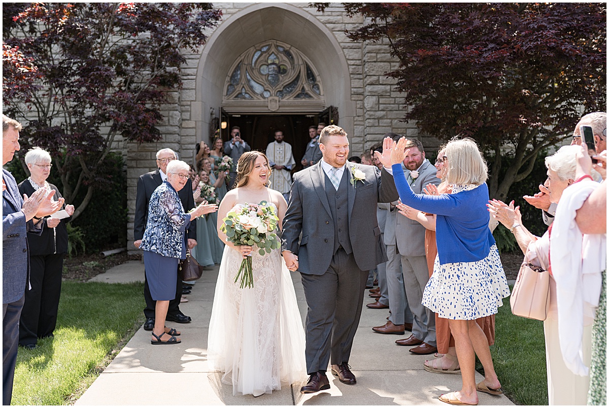Bride and groom exit church after wedding at St. Augustine Catholic Church in Rensselaer, Indiana