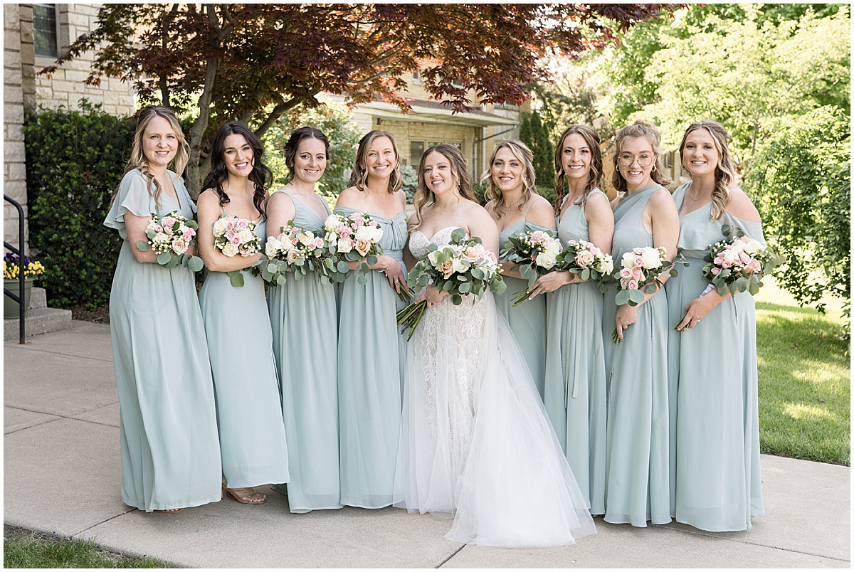 Bride and bridesmaids in light green outside wedding at St. Augustine Catholic Church in Rensselaer, Indiana