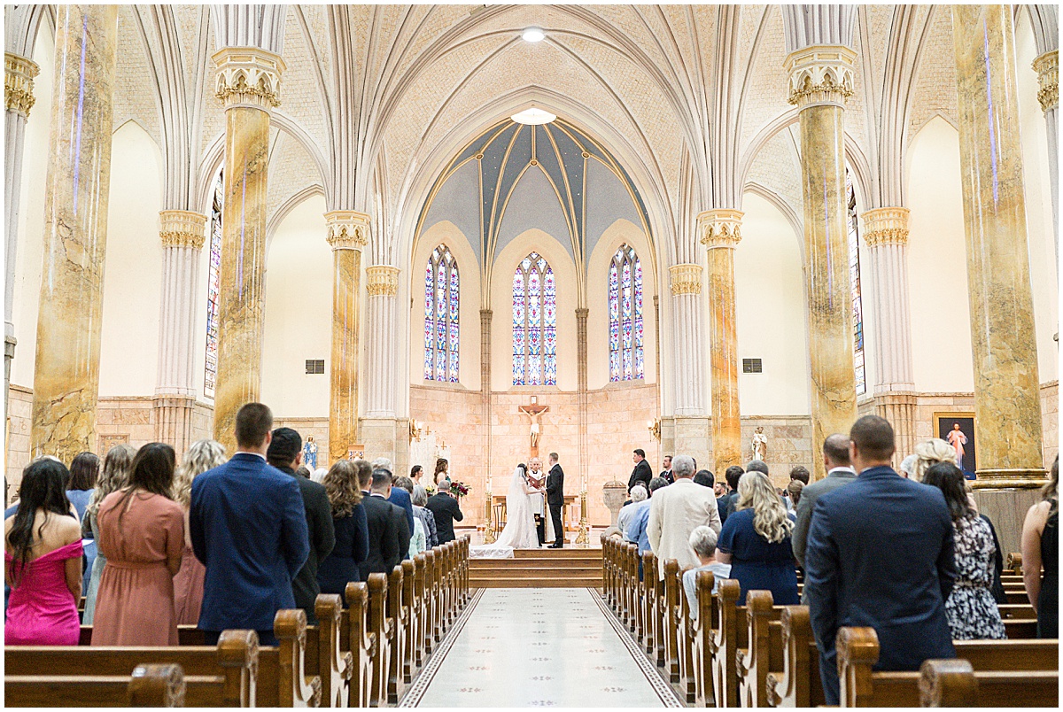 Couple standing at altar with guests standing during Saint Mary's Catholic Cathedral wedding in downtown Indianapolis