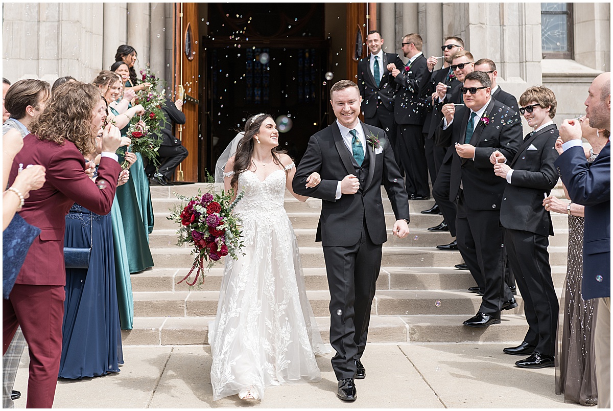 Couple making grand exit from church surrounded by bubbles after Saint Mary's Catholic Cathedral wedding in downtown Indianapolis