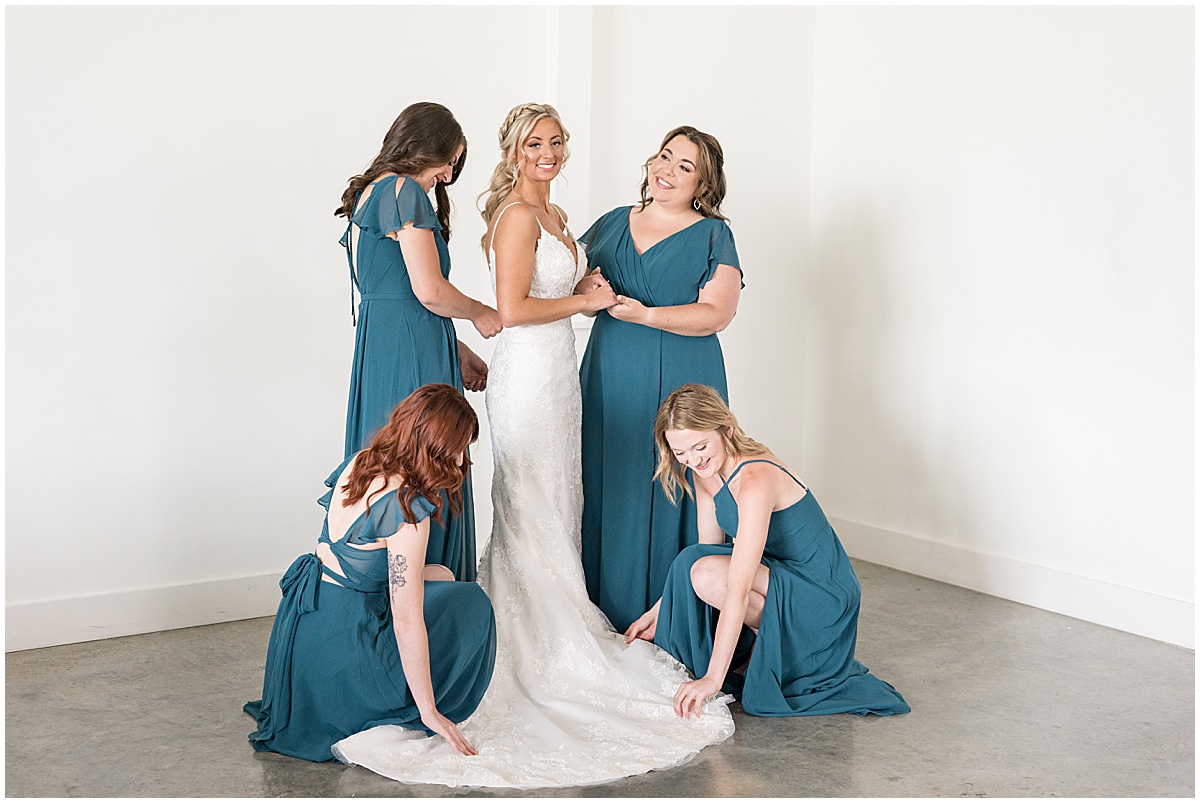 Bridesmaids in teal helping bride get ready for wedding at New Journey Farms in Lafayette, Indiana