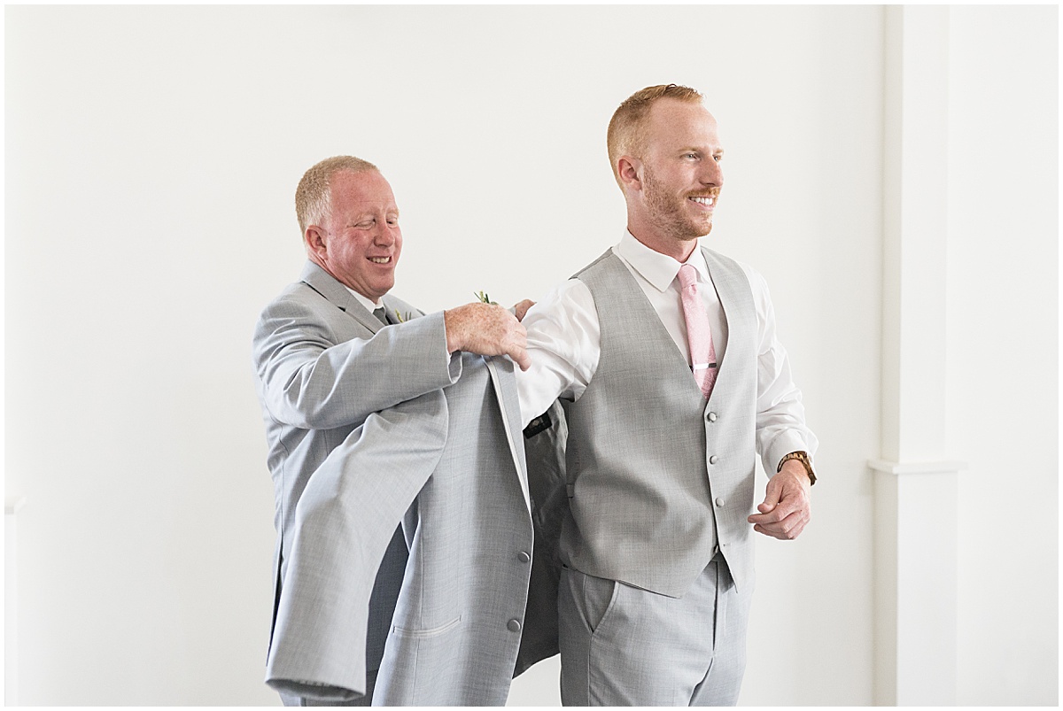 Groom putting on jacket for wedding at New Journey Farms in Lafayette, Indiana