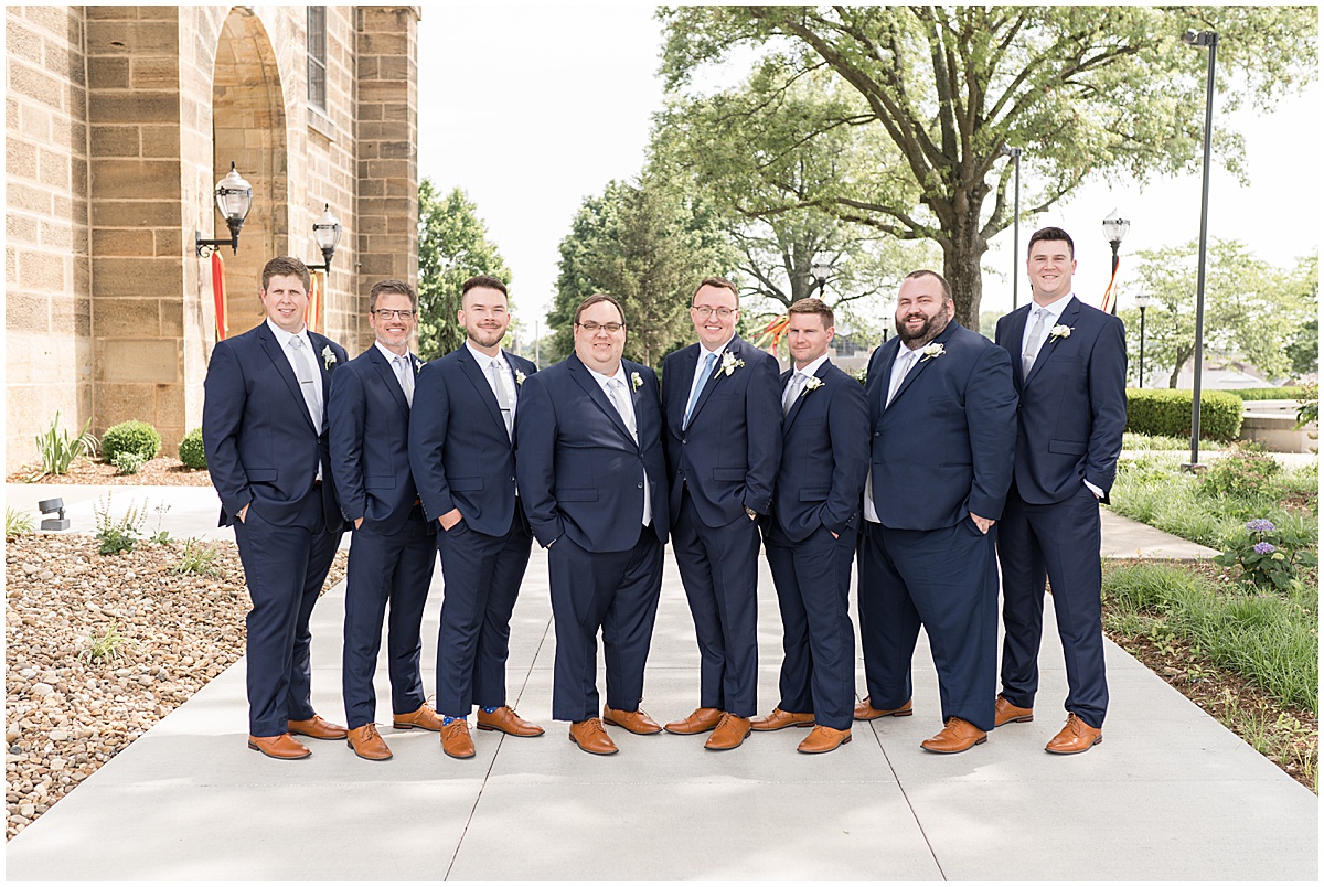 Groomsmen in navy stand together outside St. Joseph Catholic Church in Jasper, Indiana