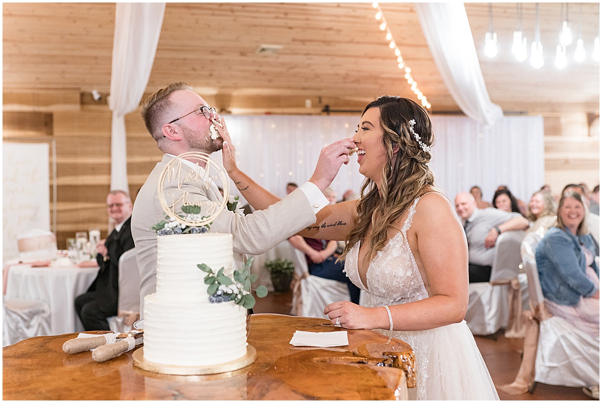 Bride and groom smash cake in their faces at Stables Event Center wedding in Lafayette, Indiana