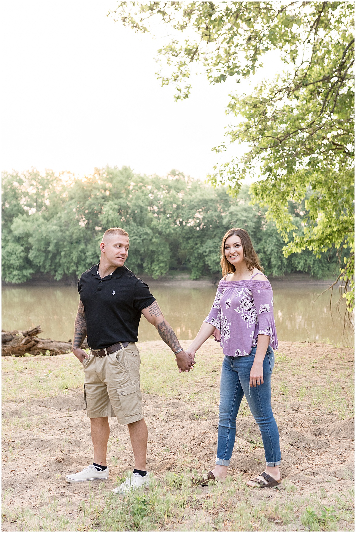 Couple walks by river at sunrise engagement photos in Lafayette, Indiana at Tapawingo Park