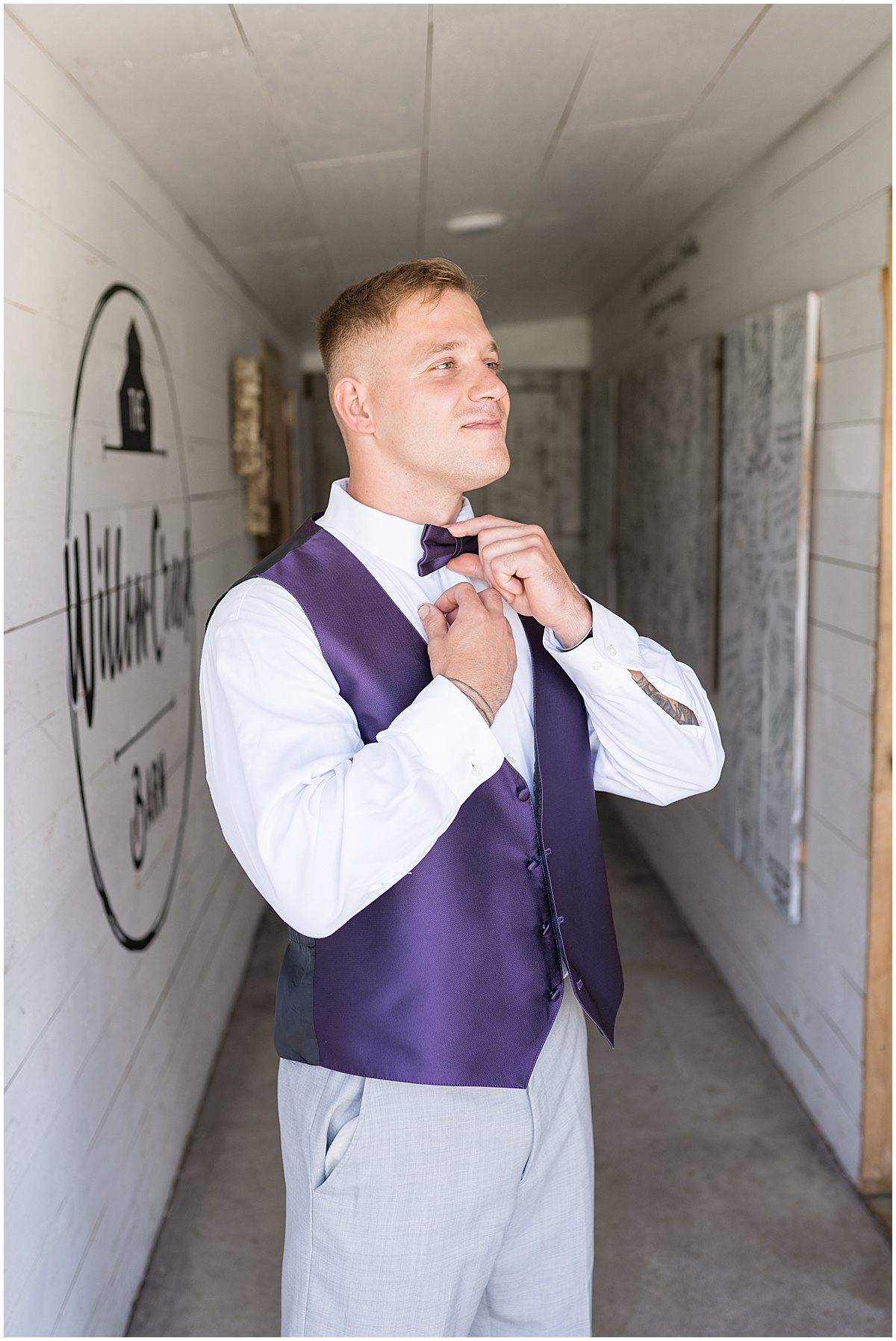 Groom puts on purple bow tie at White Willow Creek Barn wedding in Frankfort, Indiana