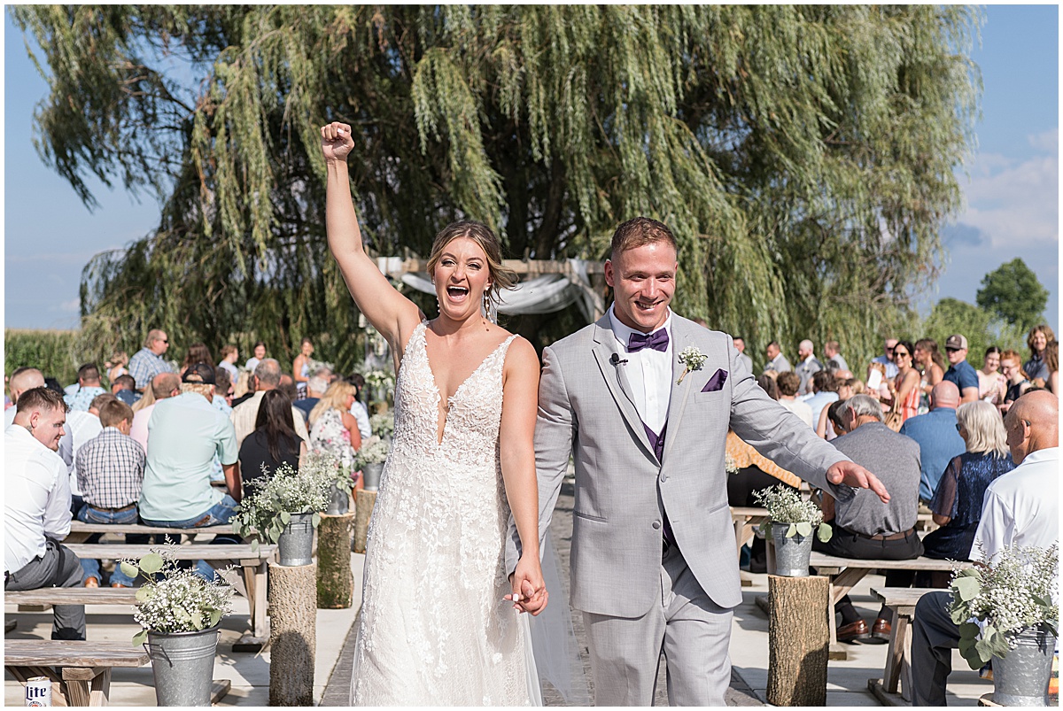 Bride and groom cheer during exit after White Willow Creek Barn wedding in Frankfort, Indiana