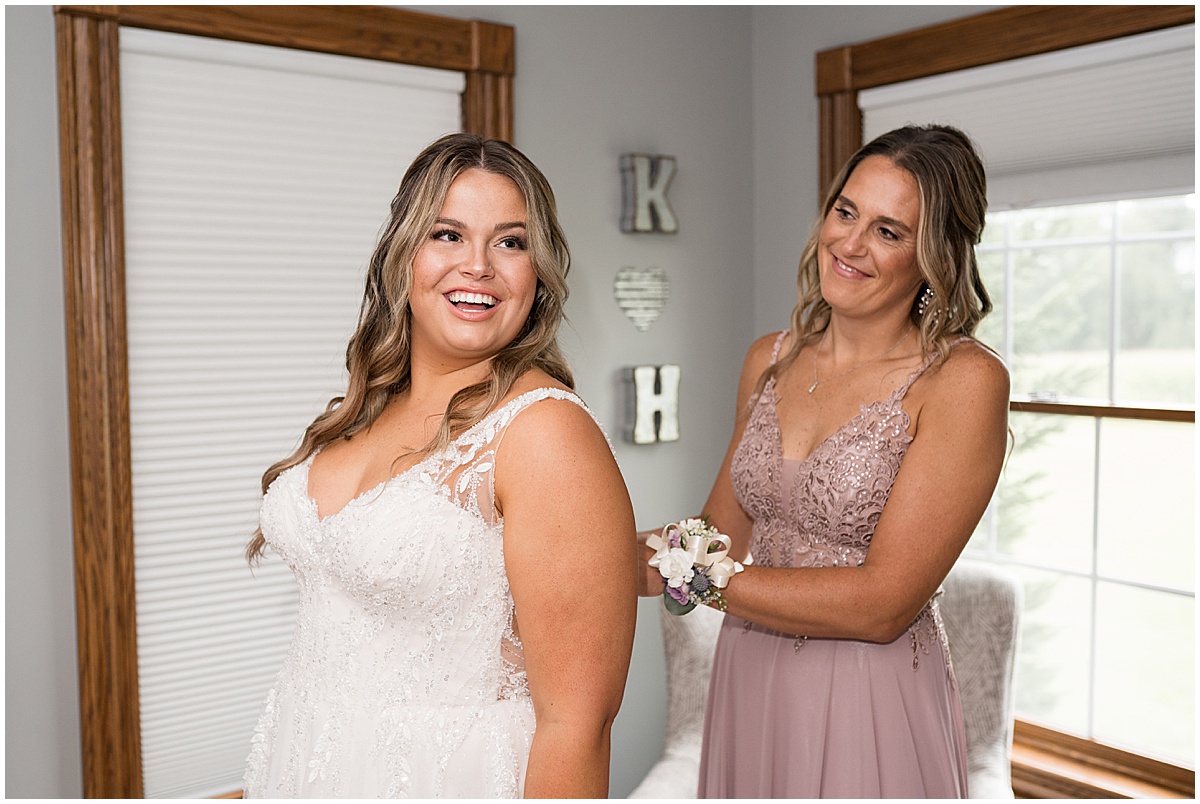 Bride has help putting on dress before private property wedding in Peru, Indiana