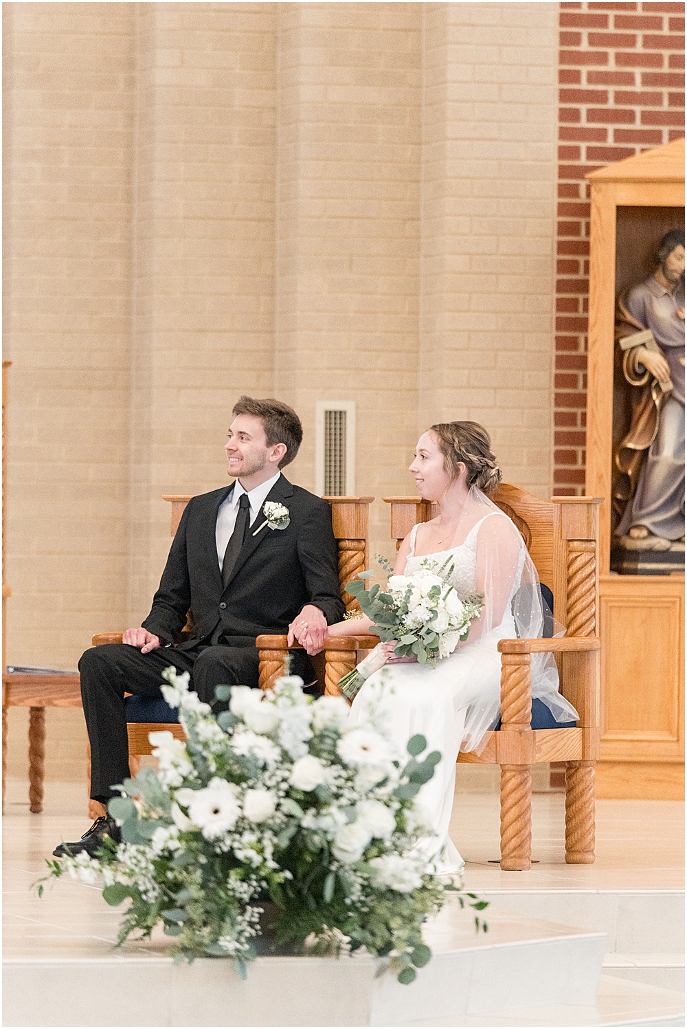 Bride and groom sitting and smiling during St. Maria Goretti Catholic Church wedding ceremony in Westfield, Indiana