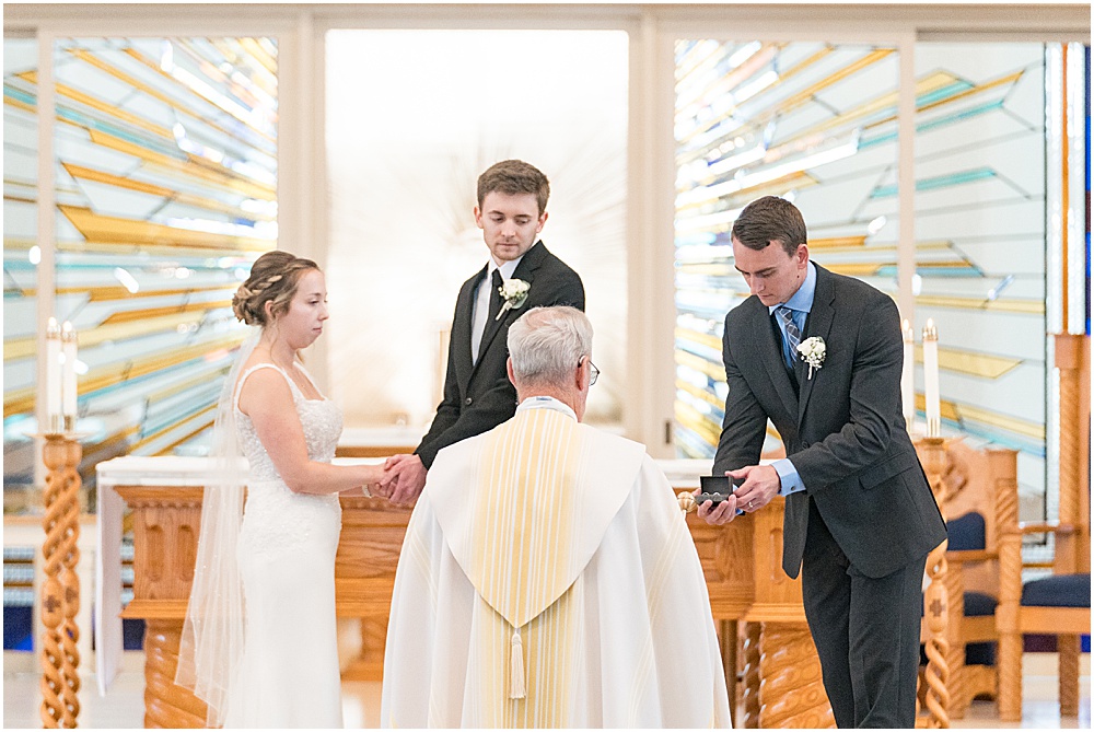 Best man gives priest rings during St. Maria Goretti Catholic Church wedding ceremony in Westfield, Indiana