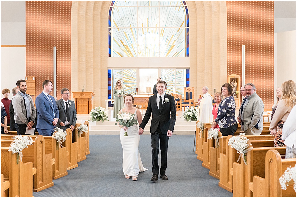 Bride and groom walk up aisle after St. Maria Goretti Catholic Church wedding ceremony in Westfield, Indiana