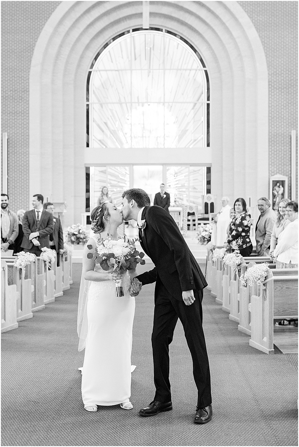 Bride and groom share kiss in aisle after St. Maria Goretti Catholic Church wedding ceremony in Westfield, Indiana